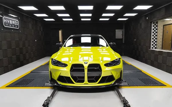 BMW G82 M4 Tuning Box S58 Strat-2. Over 605 BHP of real power. Front view of bright yellow BMW M4 in Hybrid Tune's Grey sound proof dyno cell