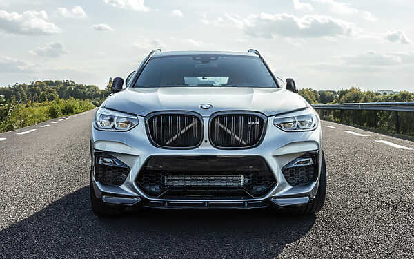 Enhanced BMW F97 X3M tuning to attain an impressive power output of 605+ BHP. Silver hybrid tunes x3m parked in the middle of the road with light clouds in the sky
