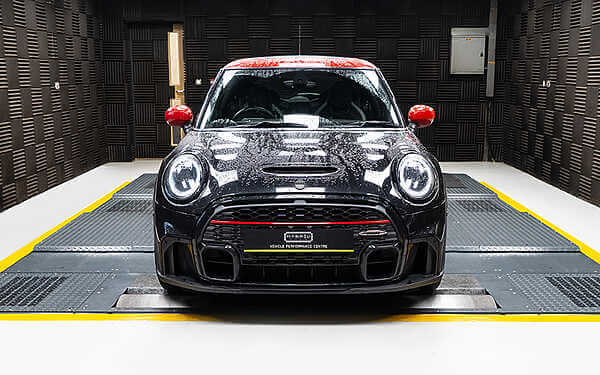 Mini F56 JCW Tuning Delivering 275+ Brake Horsepower and 378+ Newton-Meters of Torque. Rear view of a grey mini JCW strapped down in a grey dyno cell ready for a power run