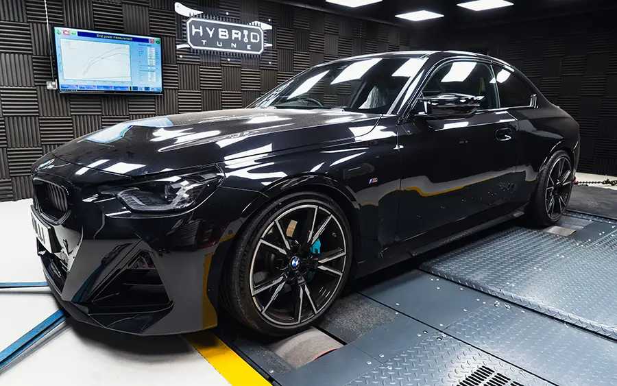 BMW M240i G42 Tuning Box B58TU Strat-2 2 Side photo of a black BMW M240i G42, black and silver wheels in a dark grey dyno cell with a blue and white floor